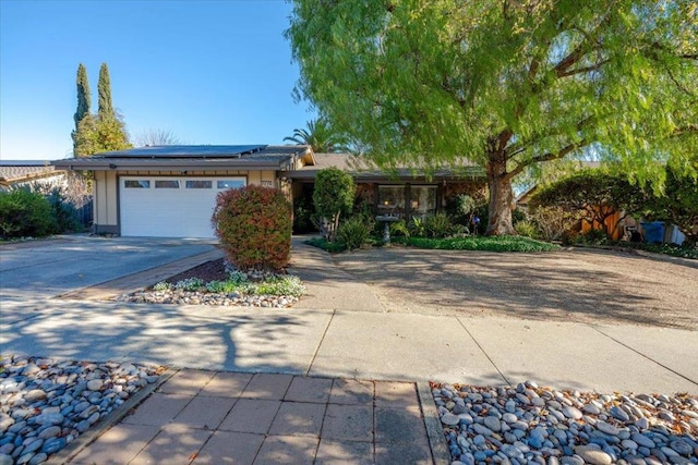 ranch-style house featuring a garage and solar panels