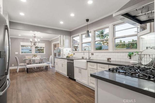 kitchen featuring sink, stainless steel appliances, decorative light fixtures, white cabinetry, and extractor fan