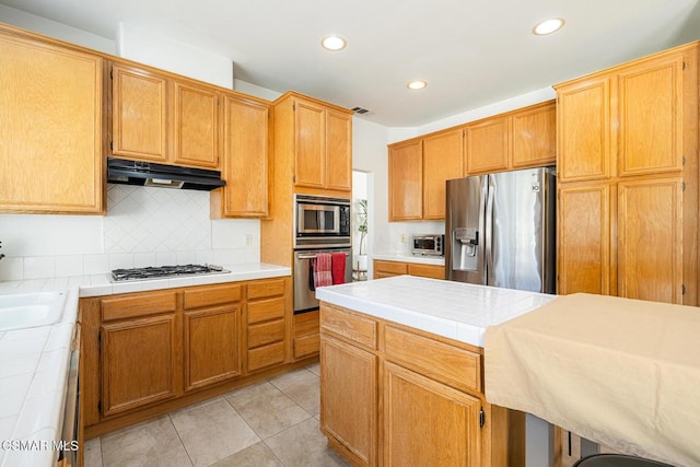 kitchen featuring stainless steel appliances, tile countertops, tasteful backsplash, and light tile patterned floors