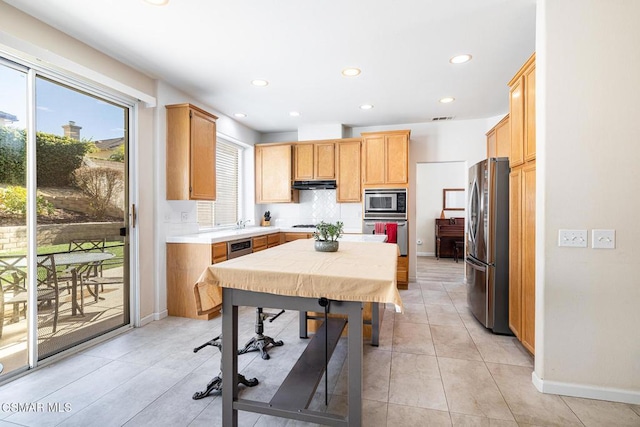 kitchen featuring stainless steel appliances, tasteful backsplash, and light brown cabinets