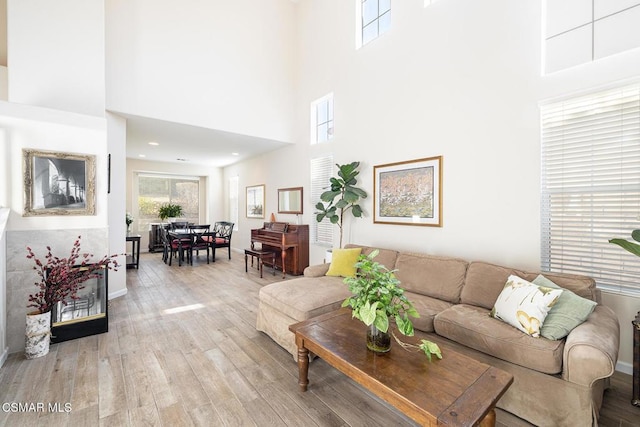 living room with light wood-type flooring and a towering ceiling