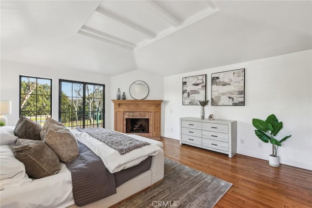 bedroom featuring dark wood-type flooring, a high end fireplace, access to exterior, and lofted ceiling with beams