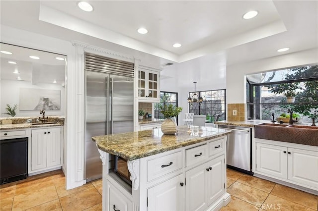 kitchen with stainless steel appliances, white cabinetry, and a tray ceiling