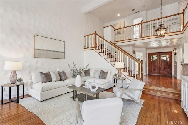 living room featuring hardwood / wood-style flooring, a towering ceiling, and an inviting chandelier