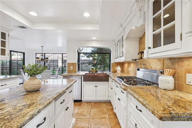 kitchen featuring sink, white cabinetry, hanging light fixtures, stainless steel appliances, and light stone counters