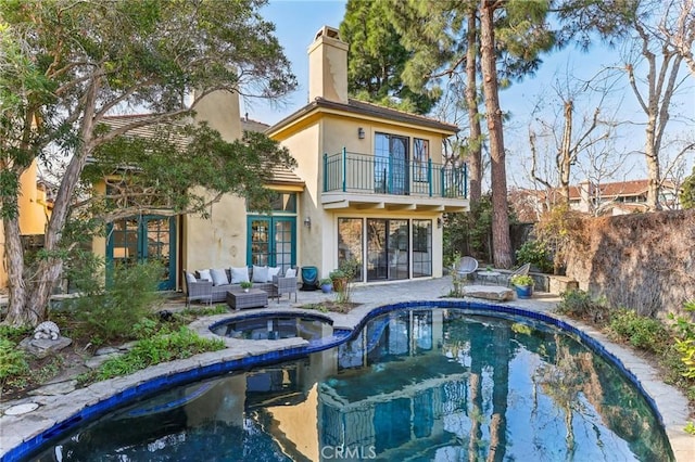 back of house with an outdoor hangout area, a pool with hot tub, a balcony, and a patio