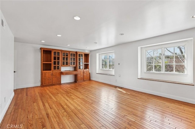 unfurnished living room featuring built in desk and light hardwood / wood-style floors