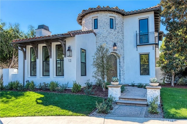 mediterranean / spanish home featuring a balcony and a front lawn