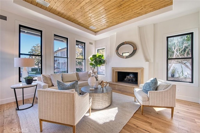 living room featuring wood ceiling, a tray ceiling, plenty of natural light, and light hardwood / wood-style floors