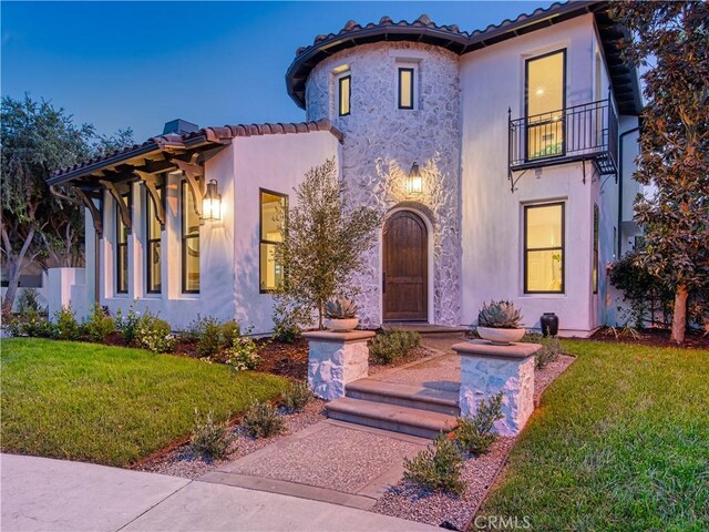 mediterranean / spanish home featuring a front lawn and a balcony