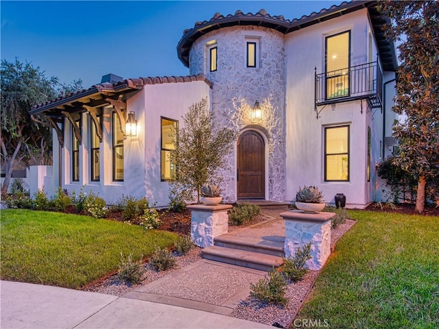 mediterranean / spanish home featuring a balcony and a front yard