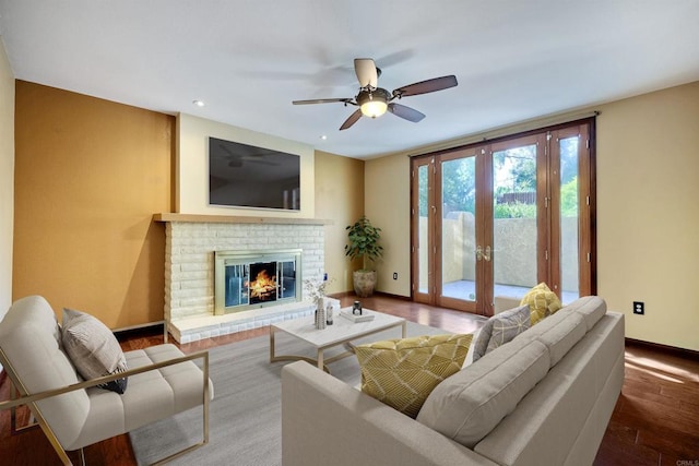 living room with ceiling fan, wood-type flooring, a brick fireplace, and french doors