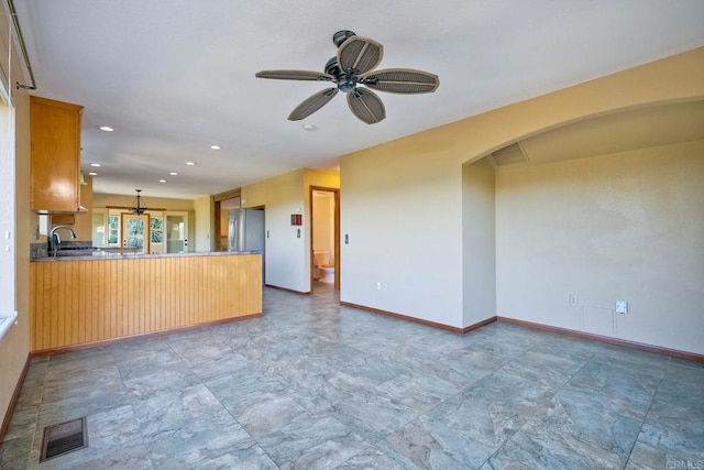 kitchen with sink, stainless steel fridge, ceiling fan, hanging light fixtures, and kitchen peninsula