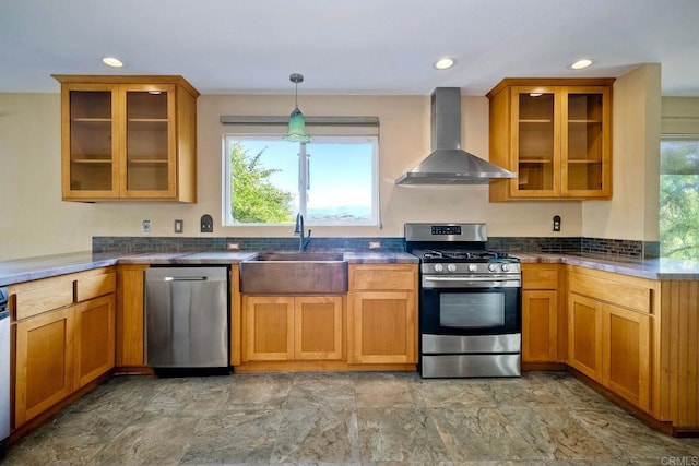 kitchen with stainless steel appliances, sink, hanging light fixtures, and wall chimney range hood