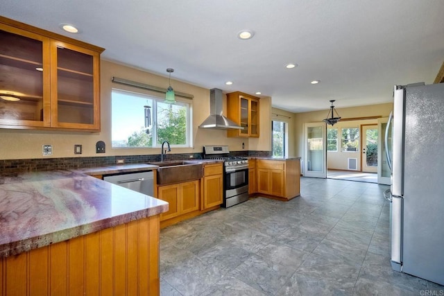 kitchen featuring sink, hanging light fixtures, appliances with stainless steel finishes, kitchen peninsula, and wall chimney range hood