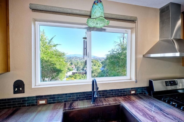 kitchen with sink, plenty of natural light, wooden counters, and wall chimney exhaust hood