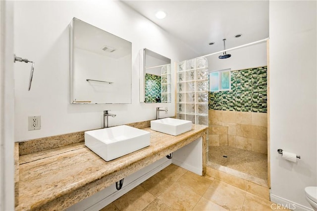 bathroom with a tile shower, vanity, and toilet