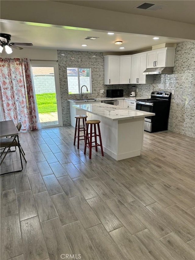 kitchen featuring a center island, electric range, white cabinets, ceiling fan, and sink