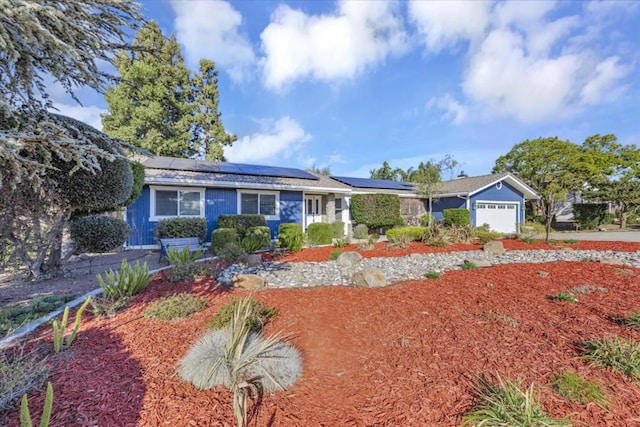 single story home featuring solar panels and a garage