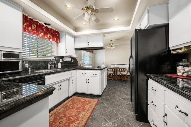 kitchen featuring white cabinets, a raised ceiling, dark tile patterned floors, and sink