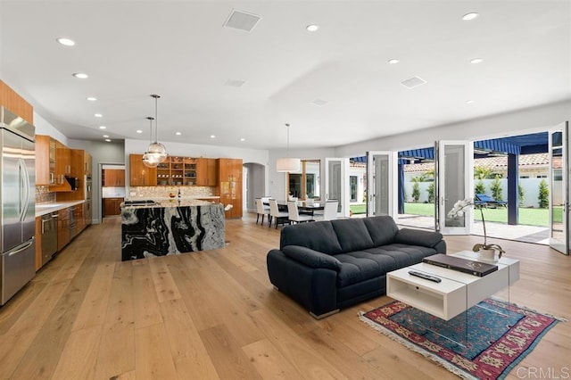 living area with light wood-style flooring, arched walkways, and recessed lighting