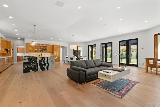 living area featuring baseboards, light wood-type flooring, arched walkways, and recessed lighting