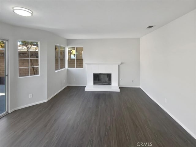 unfurnished living room with a tile fireplace and dark wood-type flooring