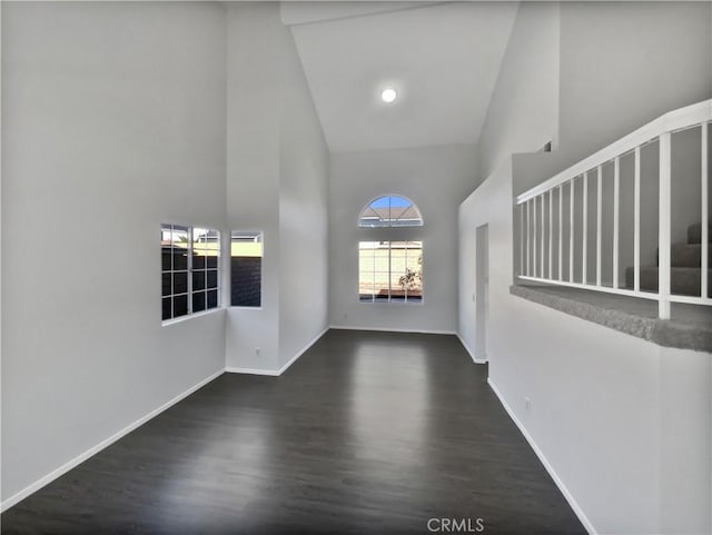 interior space with dark hardwood / wood-style floors and a towering ceiling