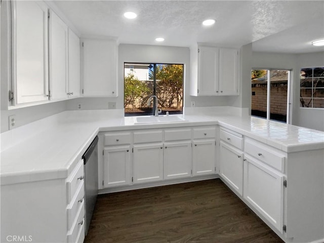 kitchen featuring white cabinets, sink, stainless steel dishwasher, and kitchen peninsula