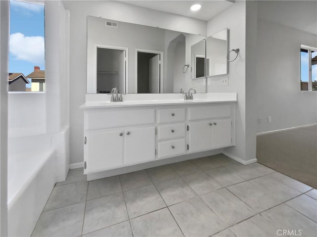 bathroom with tile patterned floors, a tub, and vanity