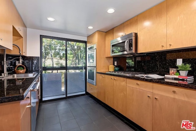 kitchen with decorative backsplash, light brown cabinetry, dark stone counters, and appliances with stainless steel finishes