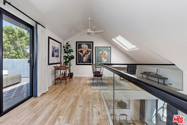 corridor featuring light wood-type flooring and vaulted ceiling with skylight