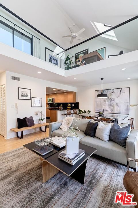 living room with a towering ceiling, hardwood / wood-style flooring, and ceiling fan