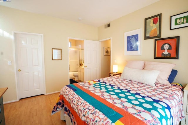 bedroom featuring connected bathroom and light wood-type flooring