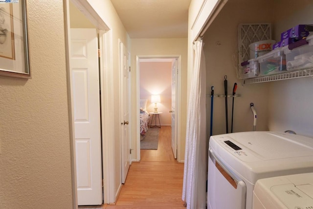 laundry area with light hardwood / wood-style flooring and washer and clothes dryer