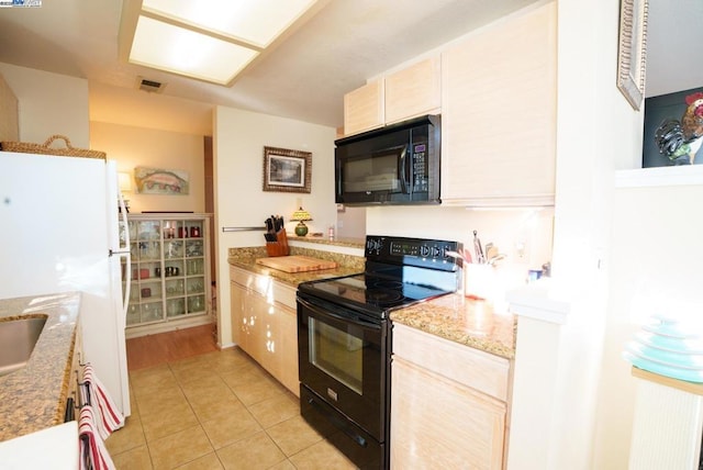 kitchen with black appliances, light stone counters, light brown cabinets, and light tile patterned floors