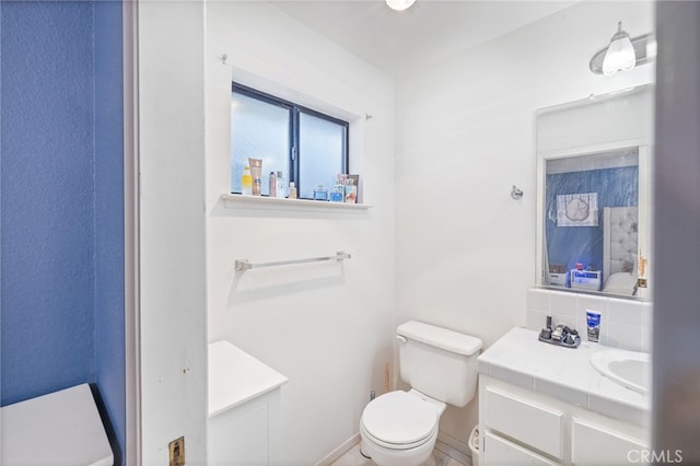 bathroom featuring toilet, vanity, and tasteful backsplash