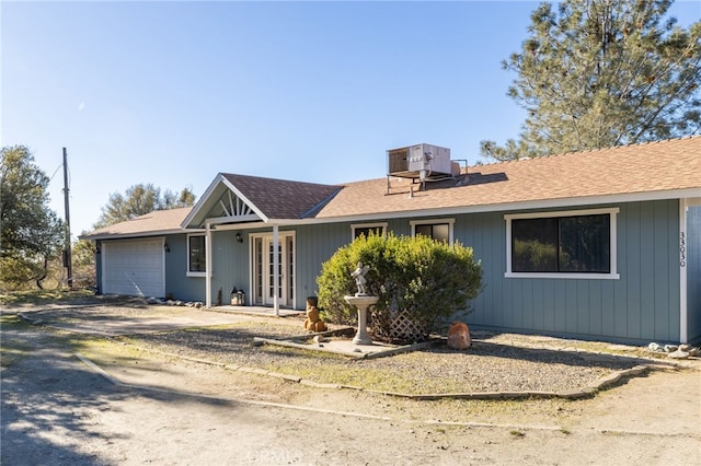 ranch-style home featuring a garage and cooling unit