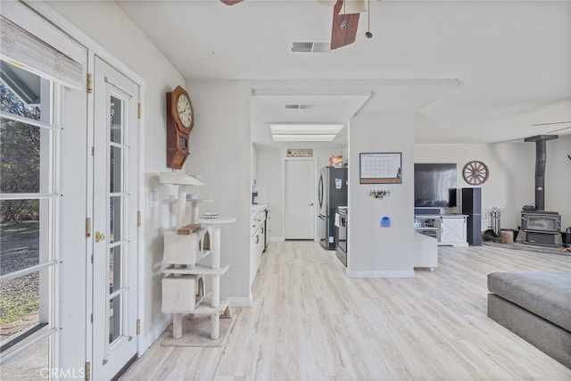 foyer entrance with light wood-type flooring and a wood stove