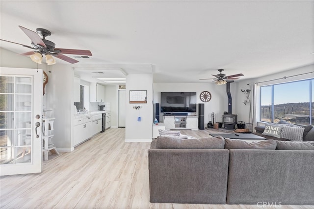 living room featuring sink, light wood-type flooring, and a wood stove