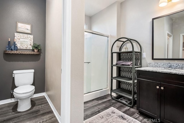 bathroom with toilet, walk in shower, vanity, and hardwood / wood-style floors