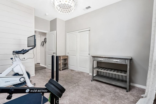 exercise room with light carpet and a chandelier