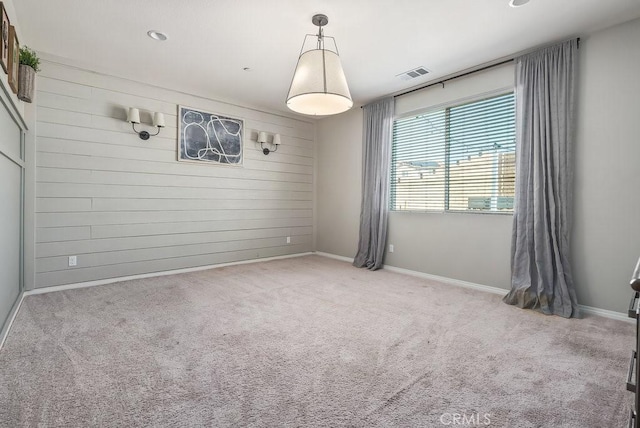 empty room with wood walls and light colored carpet