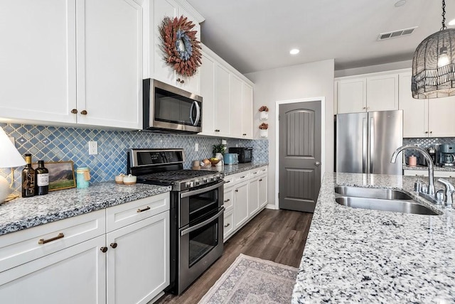 kitchen featuring sink, stainless steel appliances, white cabinetry, and pendant lighting