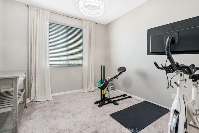 exercise area featuring light colored carpet and a chandelier