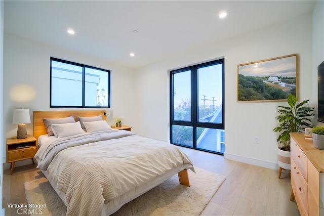 bedroom with multiple windows and light hardwood / wood-style flooring