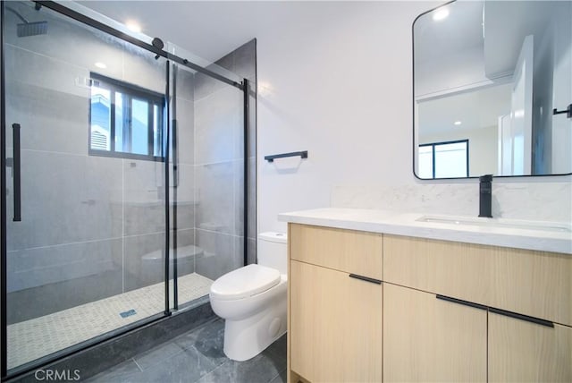 bathroom with a shower with door, vanity, a healthy amount of sunlight, and toilet