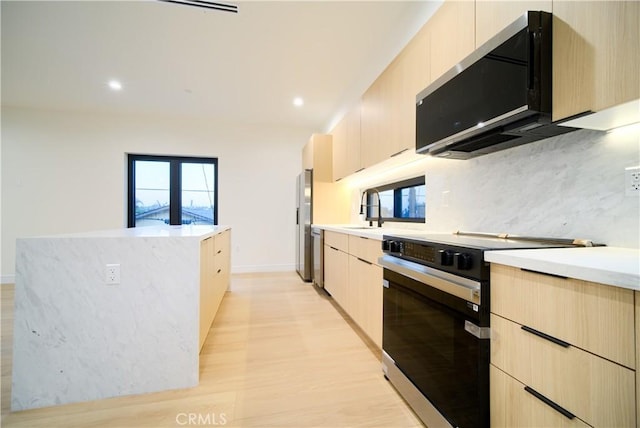 kitchen with electric range, a wealth of natural light, and light brown cabinets