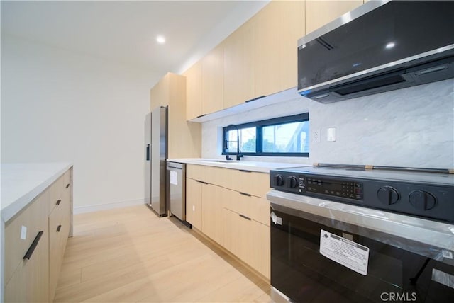 kitchen with sink, ventilation hood, light brown cabinets, light wood-type flooring, and appliances with stainless steel finishes