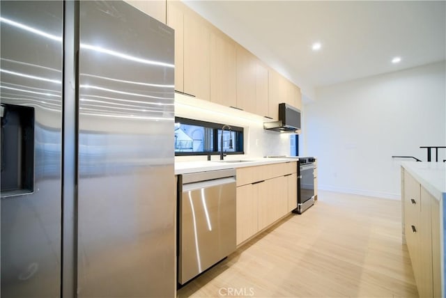 kitchen featuring stainless steel appliances, sink, and light hardwood / wood-style floors